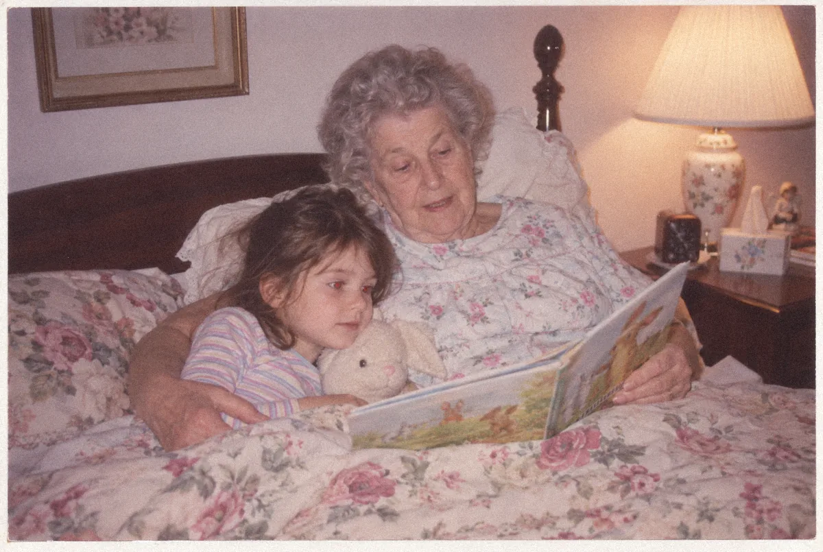 Emma as a girl, reading in bed with her grandmother