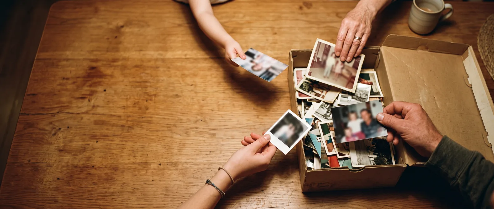 Many hands bringing photographs to one box
